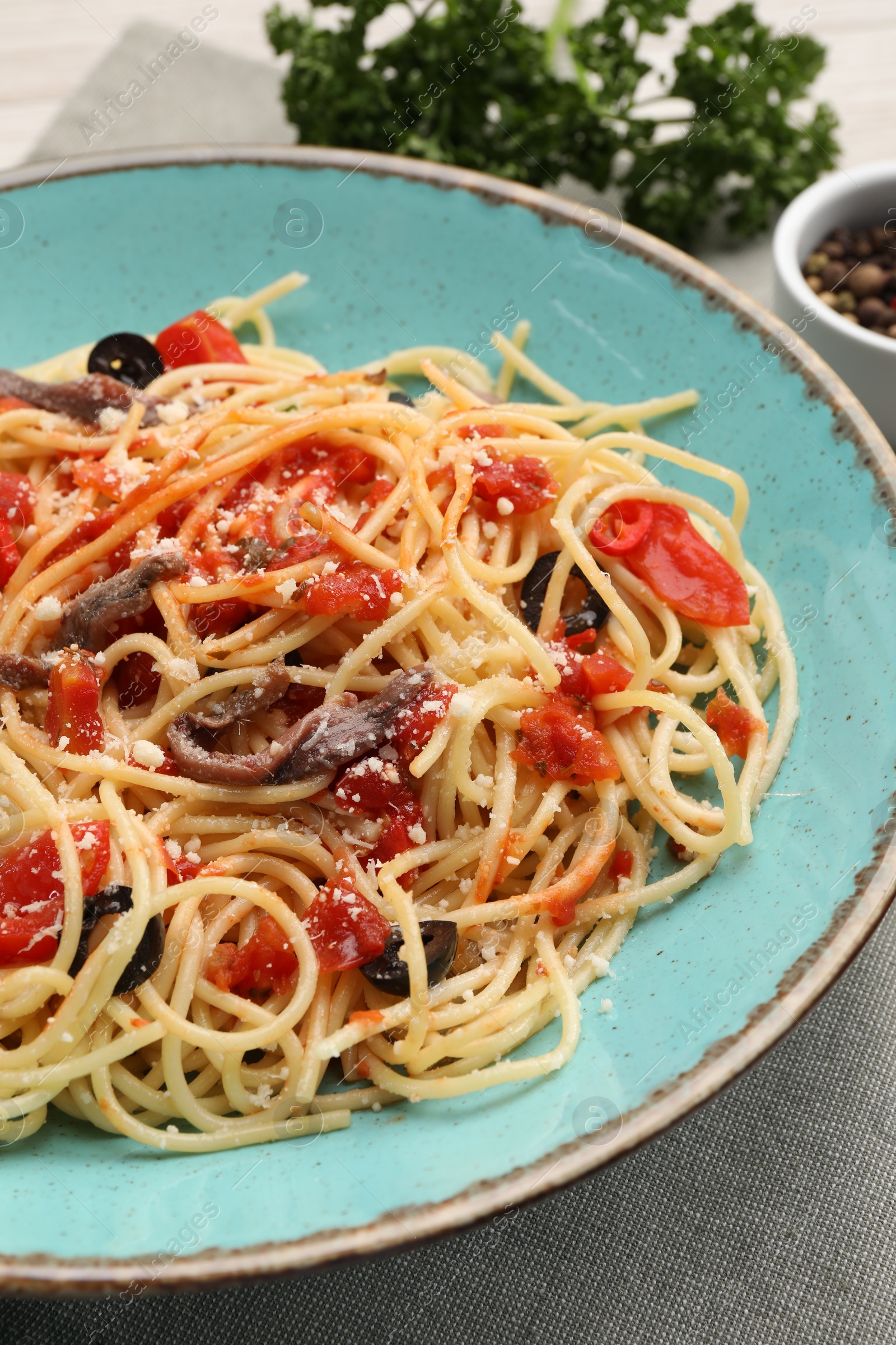 Photo of Delicious pasta with anchovies, tomatoes and parmesan cheese on table, closeup
