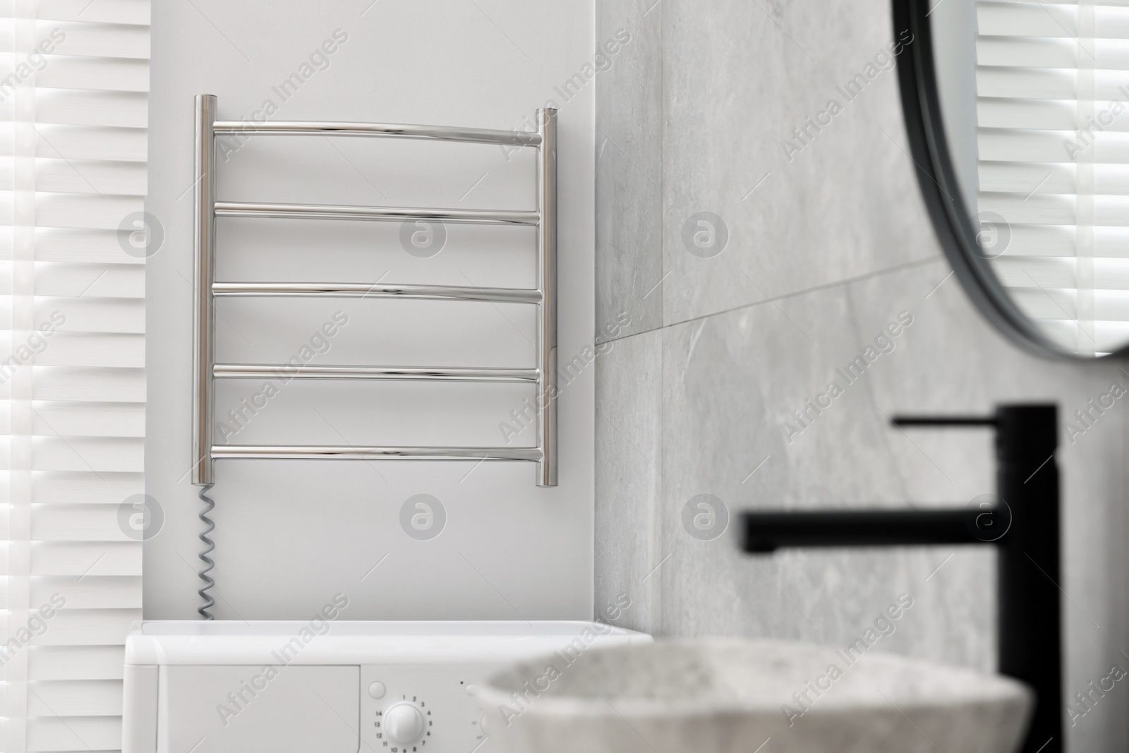 Photo of Modern heated towel rail on wall in bathroom