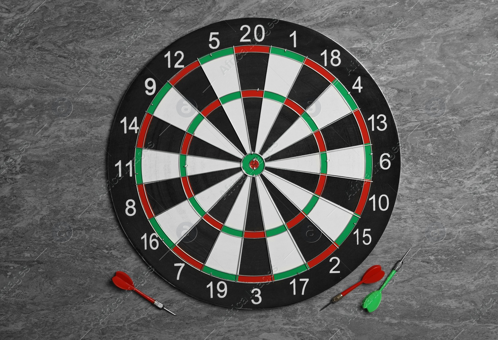 Photo of Dart board with color arrows on grey stone background, top view