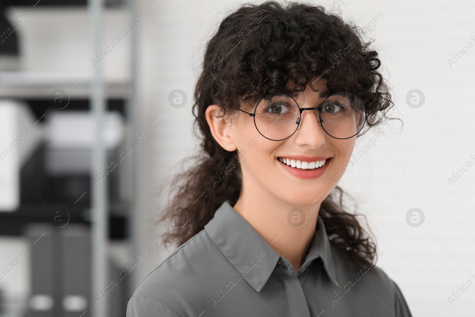 Photo of Portrait of confident entrepreneur indoors. Beautiful lady with curly hair smiling and looking into camera. Space for text