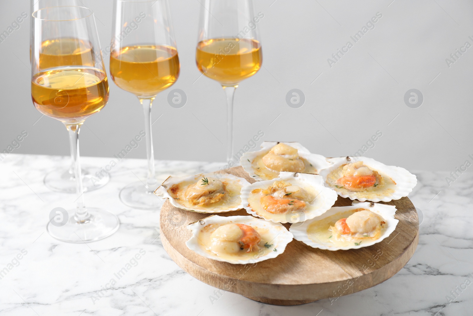 Photo of Fried scallops in shells and wine on white marble table