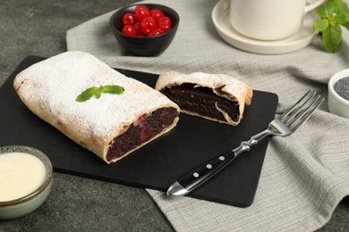 Photo of Delicious strudel with cherries and poppy seeds on grey table