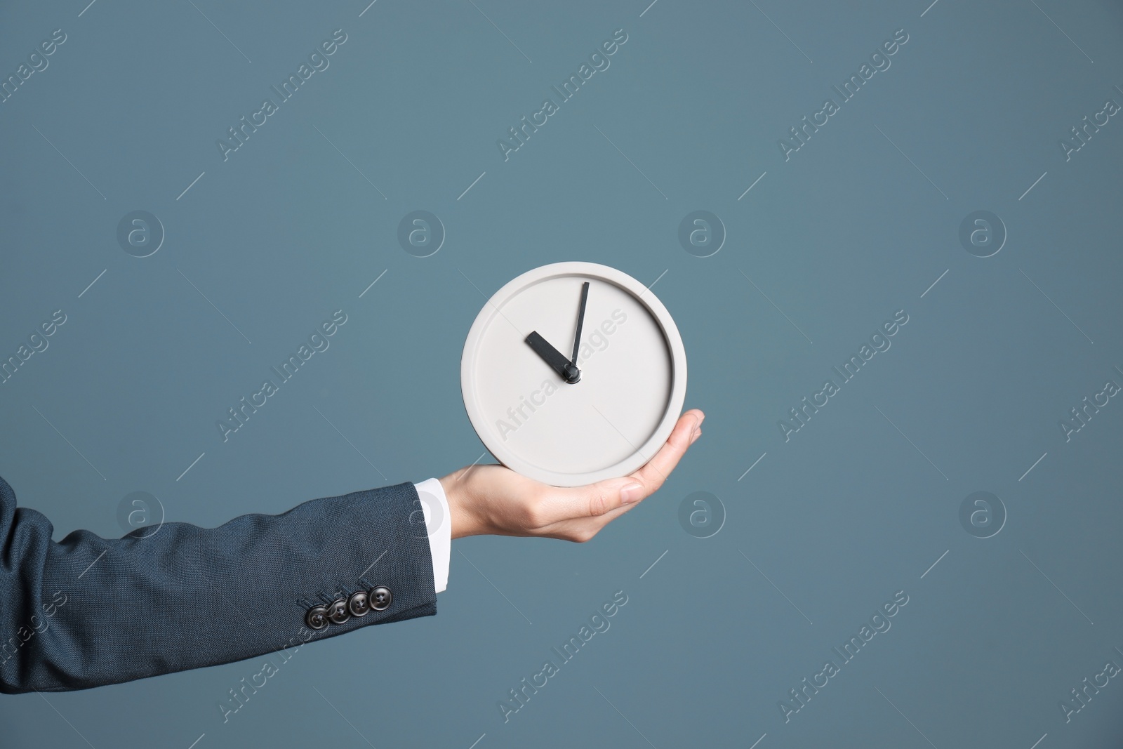 Photo of Young businesswoman holding clock on color background. Time management