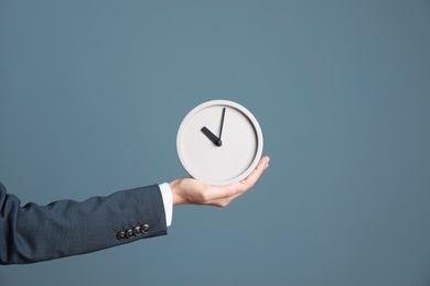 Photo of Young businesswoman holding clock on color background. Time management