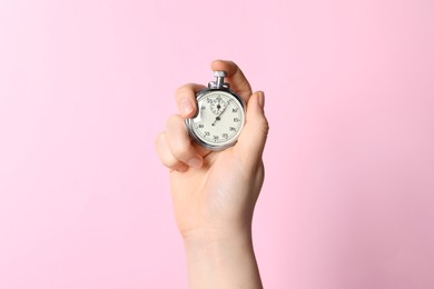 Photo of Woman holding vintage timer on pink background, closeup