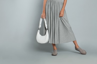 Woman with stylish bag on grey background, closeup