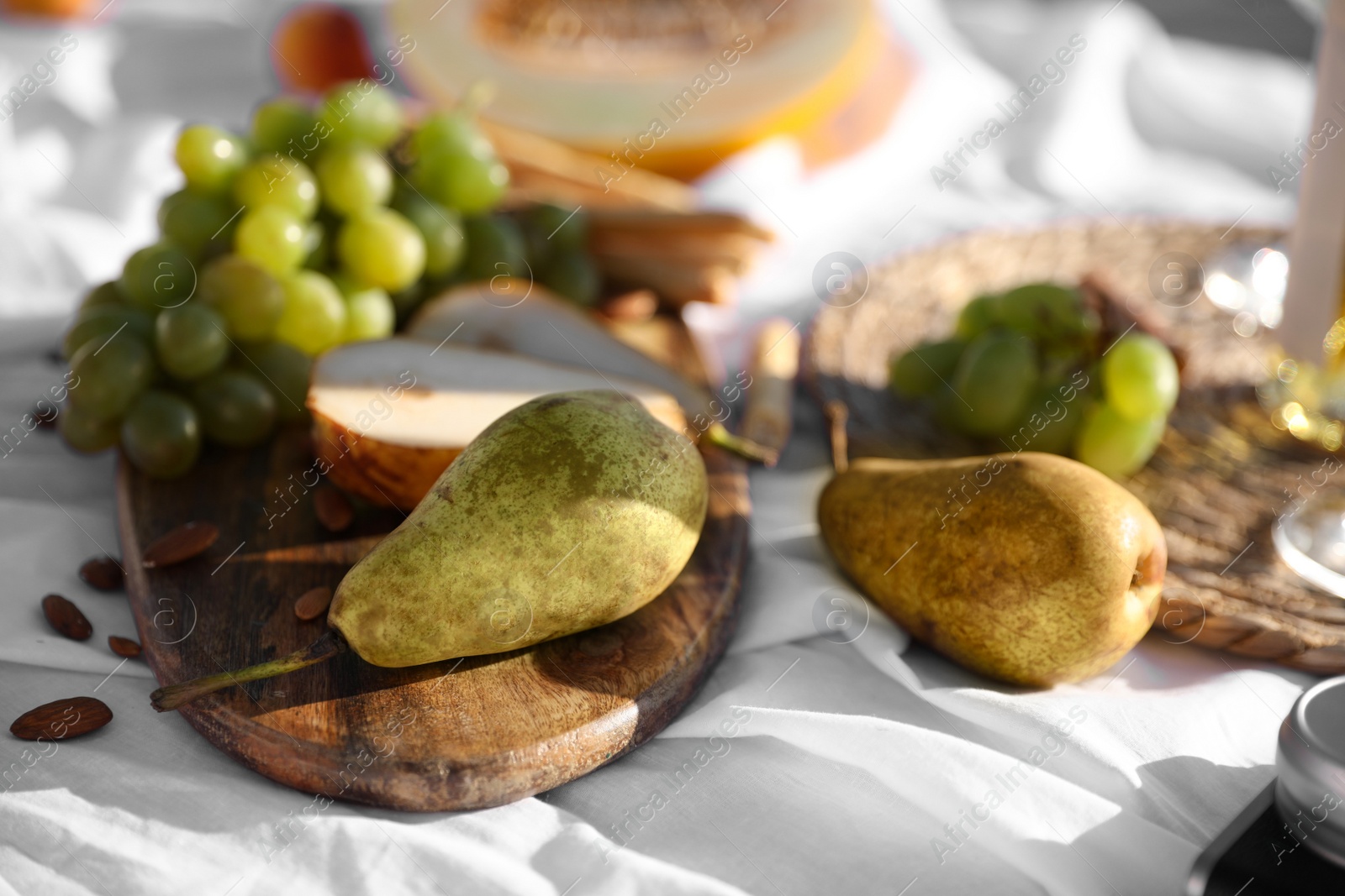 Photo of Delicious pears and grapes on picnic blanket, closeup