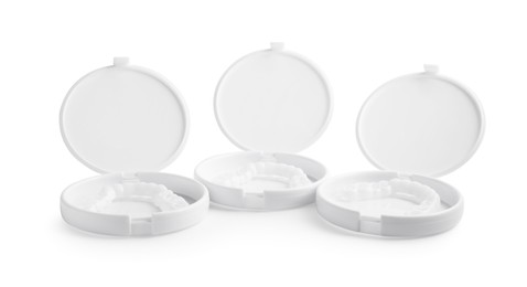 Photo of Containers with dental mouth guards on white background. Bite correction