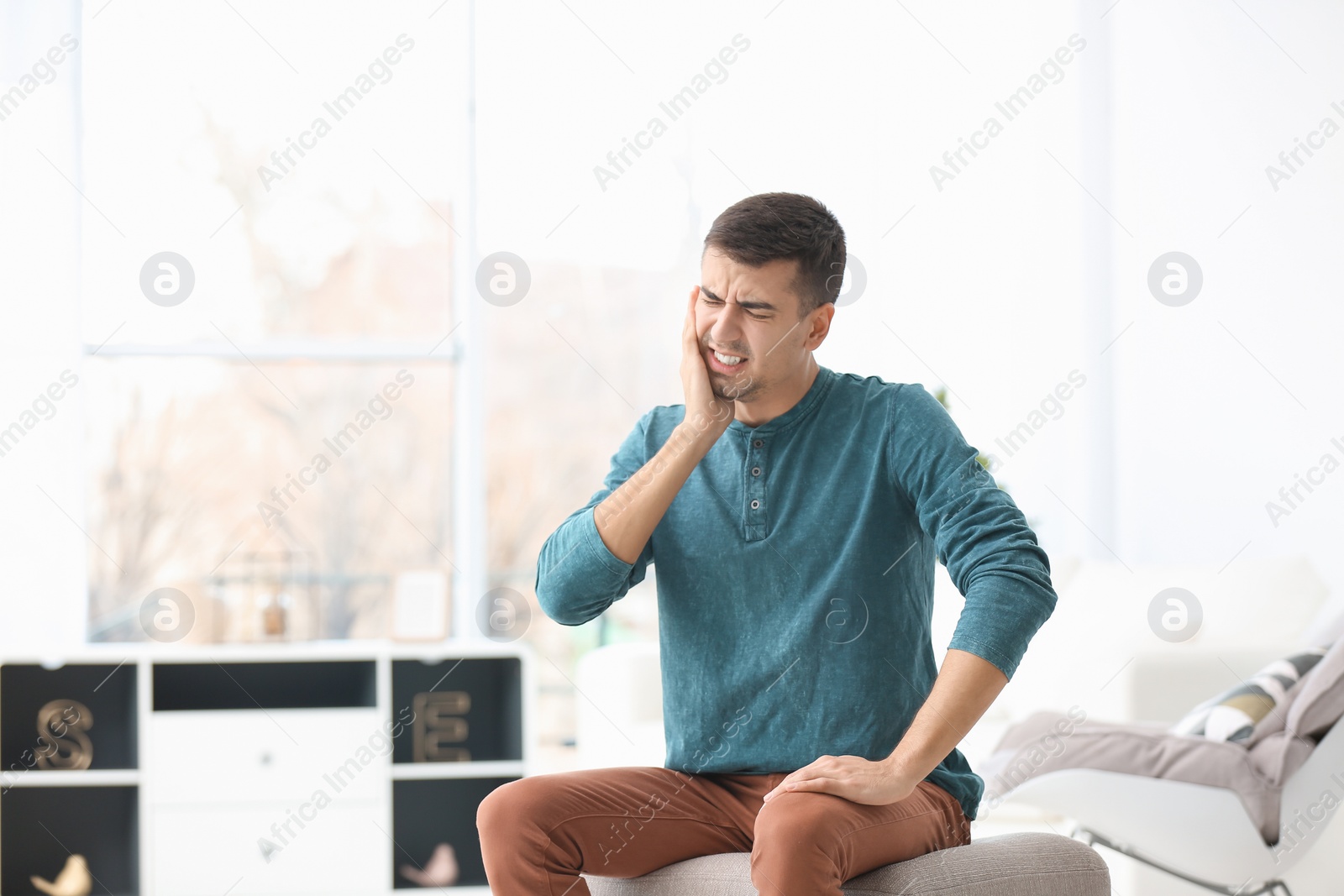 Photo of Young man suffering from toothache  at home