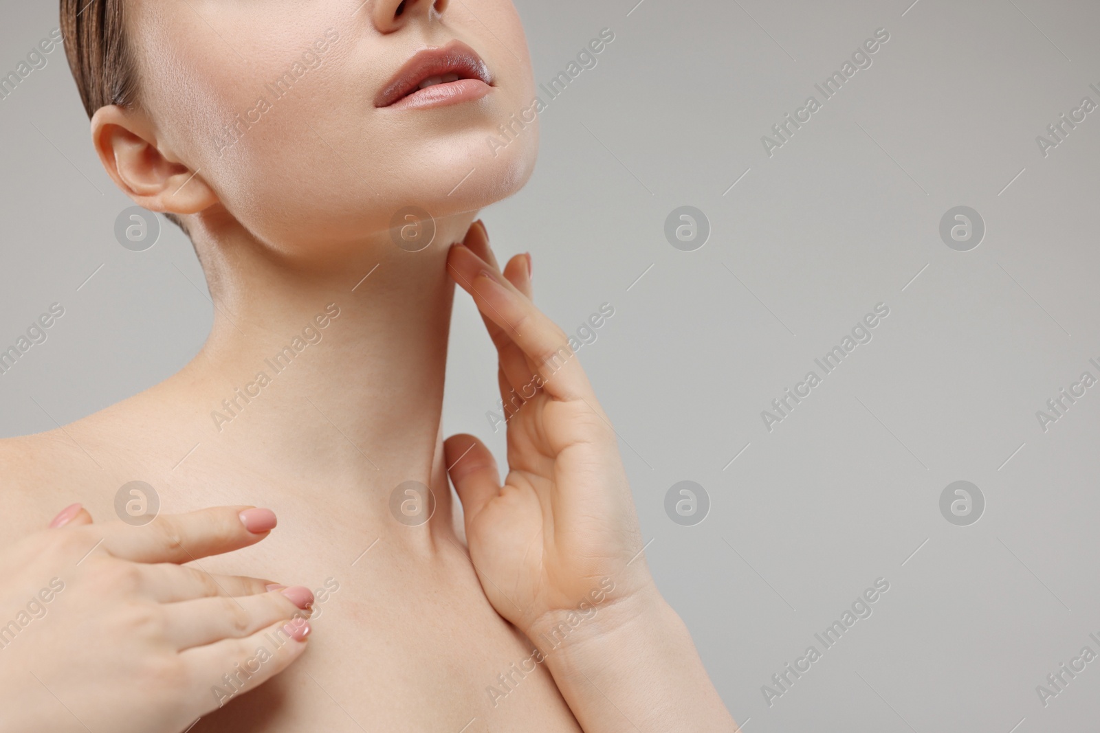 Photo of Woman touching her neck on grey background, closeup. Space for text