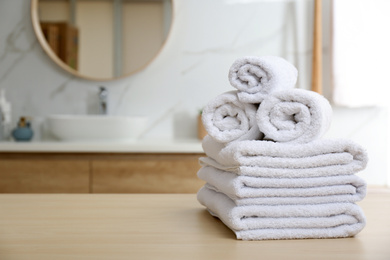 Photo of White towels on wooden table in bathroom. Space for text