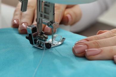 Photo of Seamstress working with sewing machine indoors, selective focus