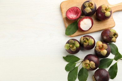 Photo of Fresh ripe mangosteen fruits on white wooden table, flat lay. Space for text