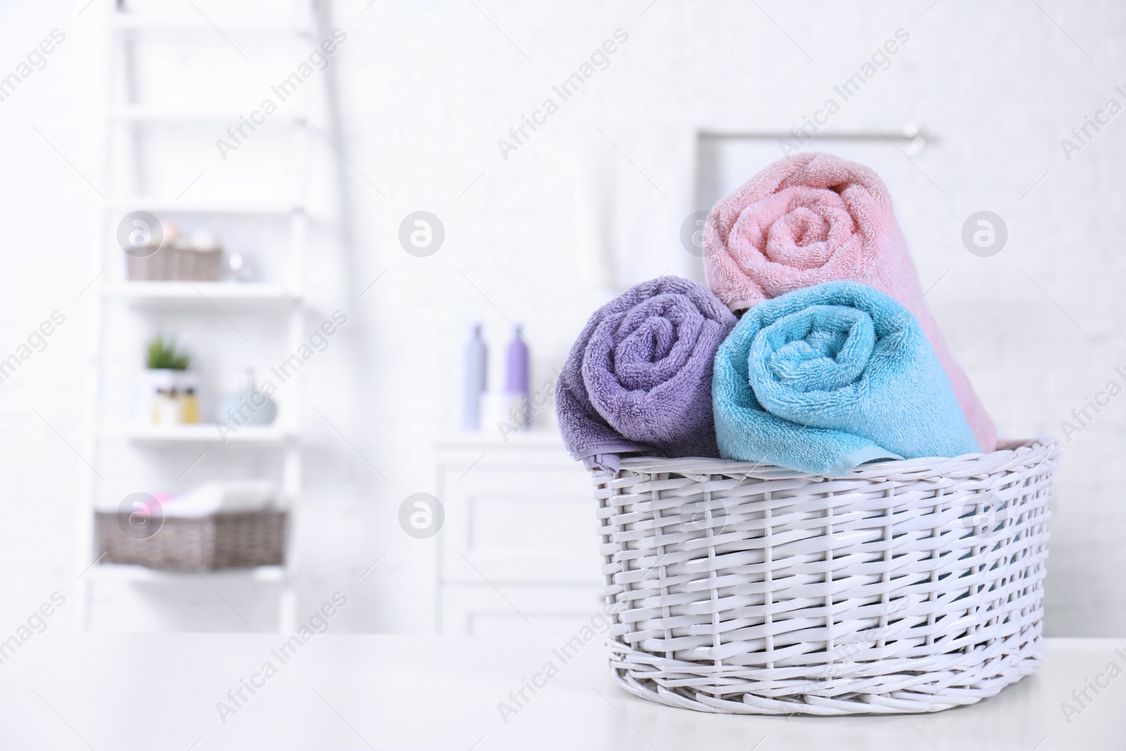 Photo of Basket with rolled fresh towels on table in bathroom. Space for text