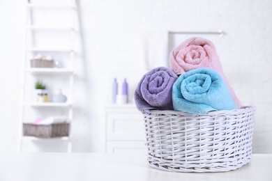 Basket with rolled fresh towels on table in bathroom. Space for text