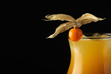 Tasty cocktail decorated with physalis fruit on black background, closeup. Space for text