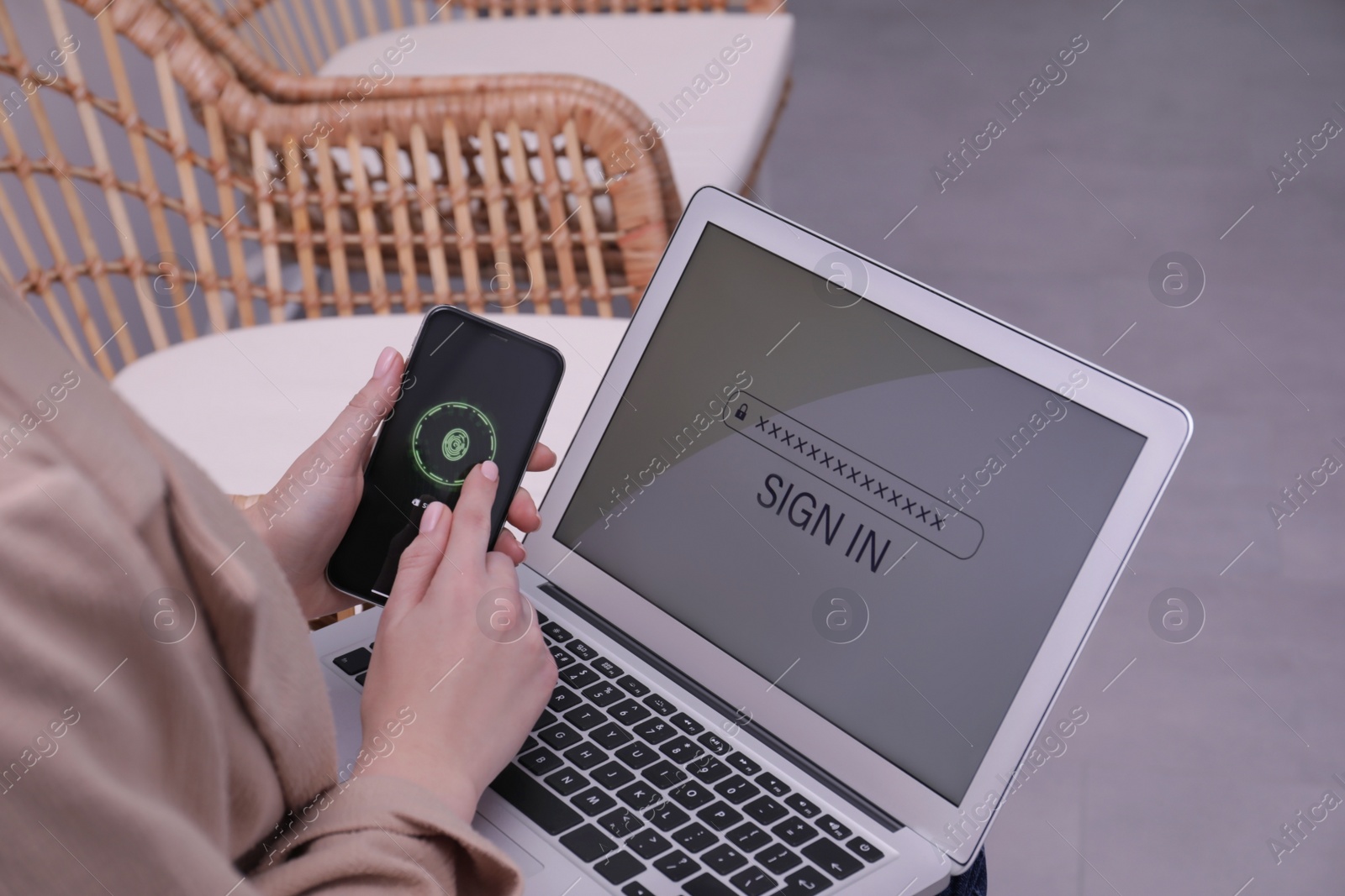 Photo of Woman unlocking smartphone with fingerprint scanner, closeup. Her laptop password protected to