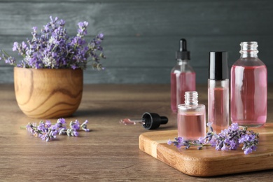 Photo of Bottles of essential oil and lavender flowers on wooden table