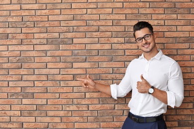 Portrait of handsome young man and space for text on brick wall background