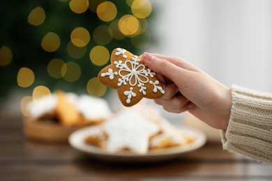 Woman with decorated Christmas cookie at table, closeup