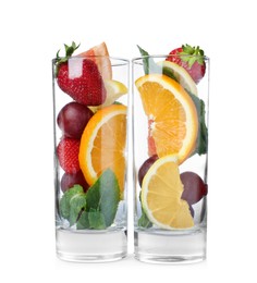 Photo of Glasses with different whole and cut fruits on white background