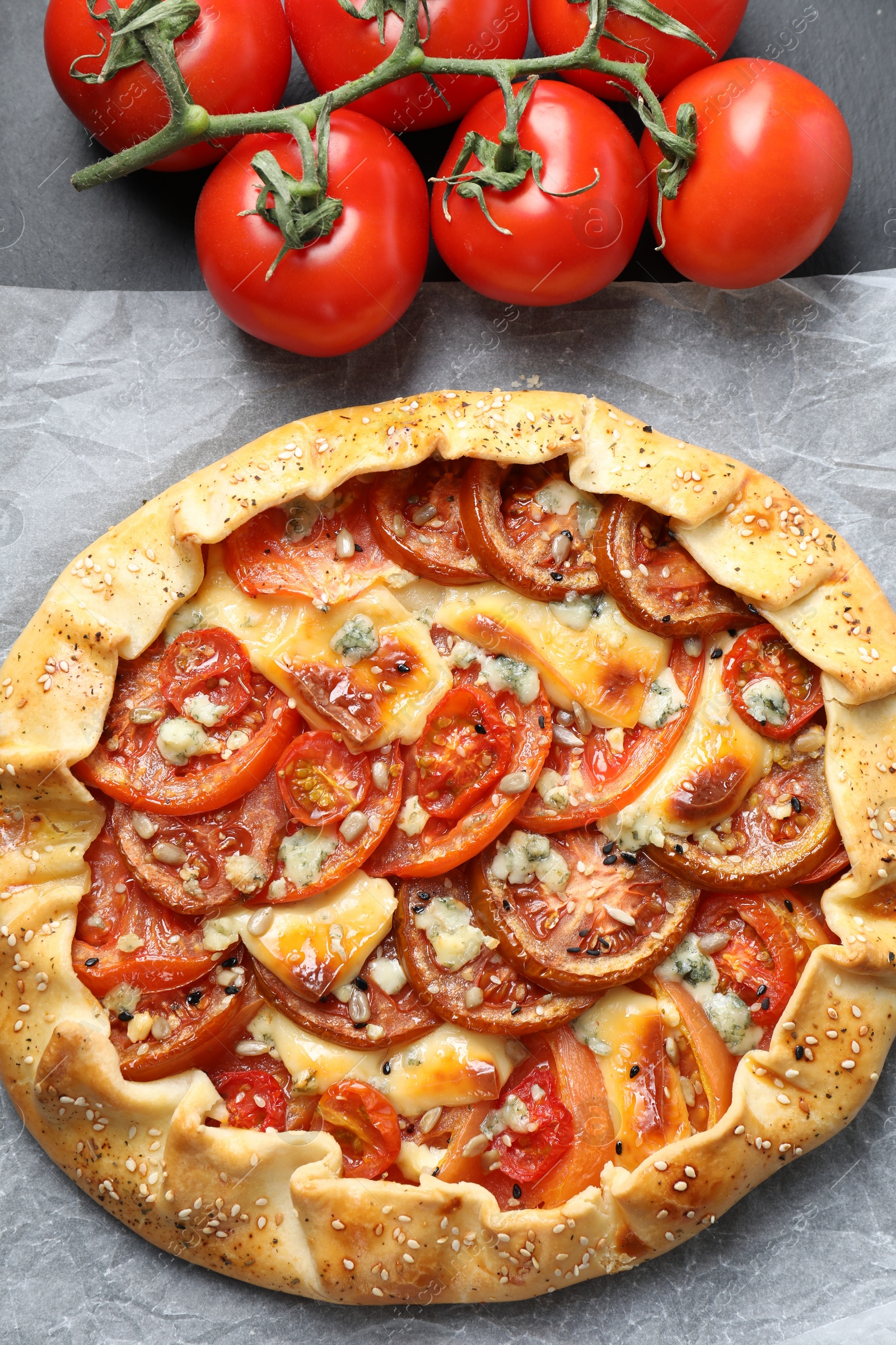 Photo of Tasty galette with tomato and cheese (Caprese galette) on dark table, top view