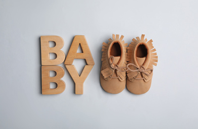 Photo of Flat lay composition with child's booties and word Baby on light background