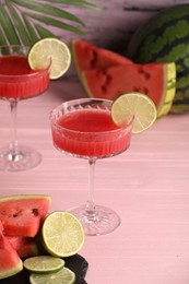 Cocktail glass of delicious fresh watermelon juice with lime on light wooden table