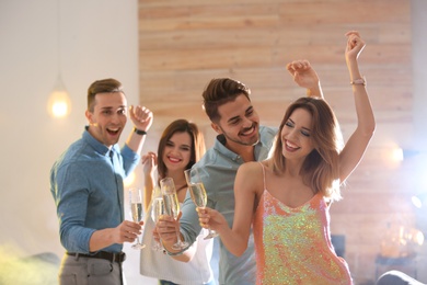 Happy friends with champagne in glasses having party indoors