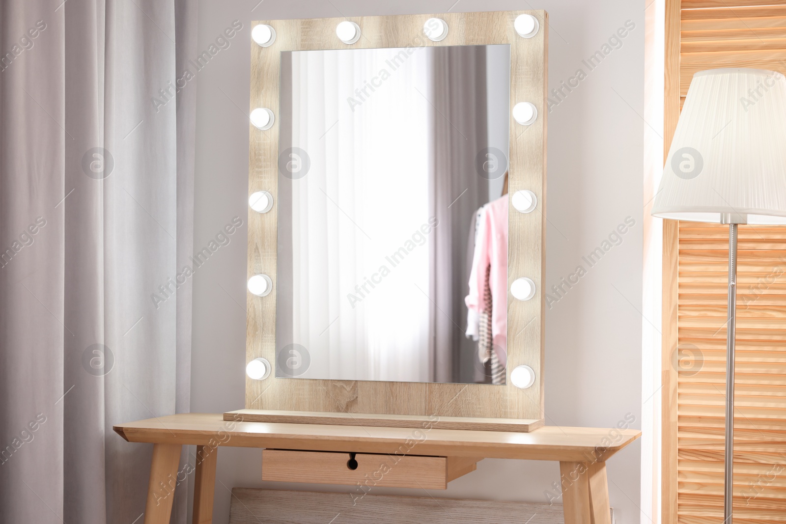 Photo of Beautiful mirror with light bulbs and lamp in makeup room