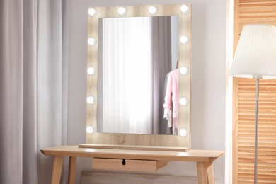 Photo of Beautiful mirror with light bulbs and lamp in makeup room