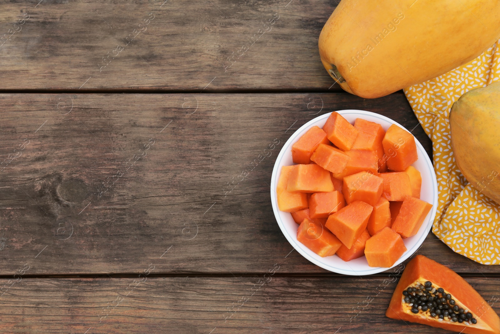 Photo of Tasty whole and cut papaya fruits on wooden table, flat lay. Space for text