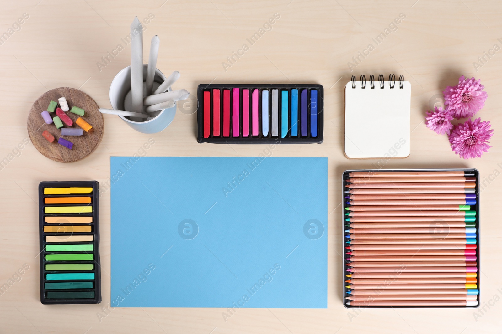 Photo of Layout with blank papers, soft pastels and other drawing supplies on wooden table at artist's workplace, top view. Space for design