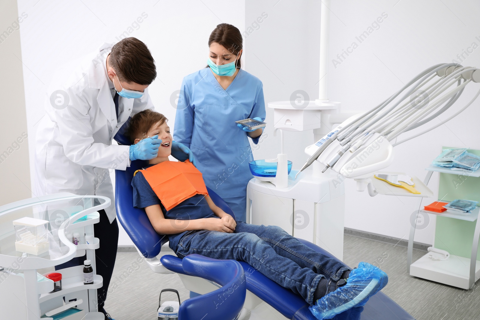 Photo of Professional dentist and assistant working with little boy in clinic