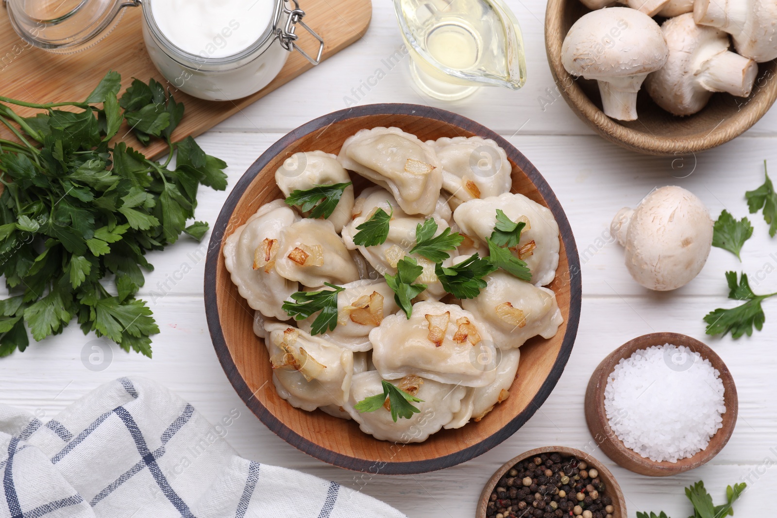 Photo of Delicious dumplings (varenyky) with potatoes, onion and parsley served on white wooden table, flat lay