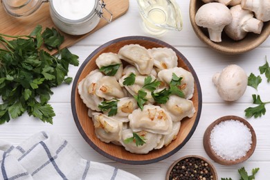 Delicious dumplings (varenyky) with potatoes, onion and parsley served on white wooden table, flat lay