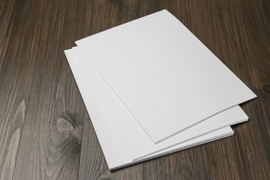 Photo of Stack of blank paper sheets on wooden table. Brochure design