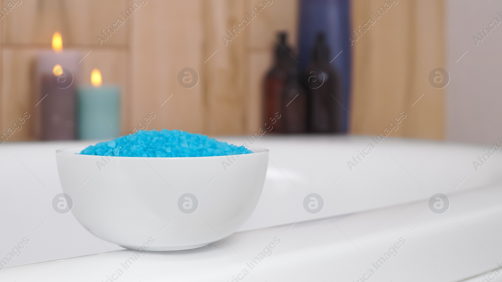 Photo of Bowl with sea salt on white bath. Space for text