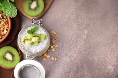 Photo of Delicious dessert with kiwi, fresh cut fruits and muesli on brown table, flat lay. Space for text