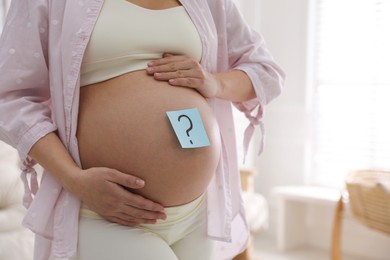 Photo of Pregnant woman with sticky note on belly at home, closeup. Choosing baby name