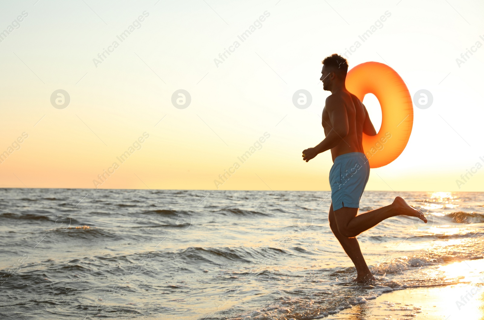 Photo of Young man with inflatable ring on beach