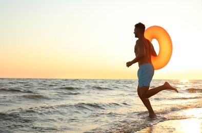 Photo of Young man with inflatable ring on beach