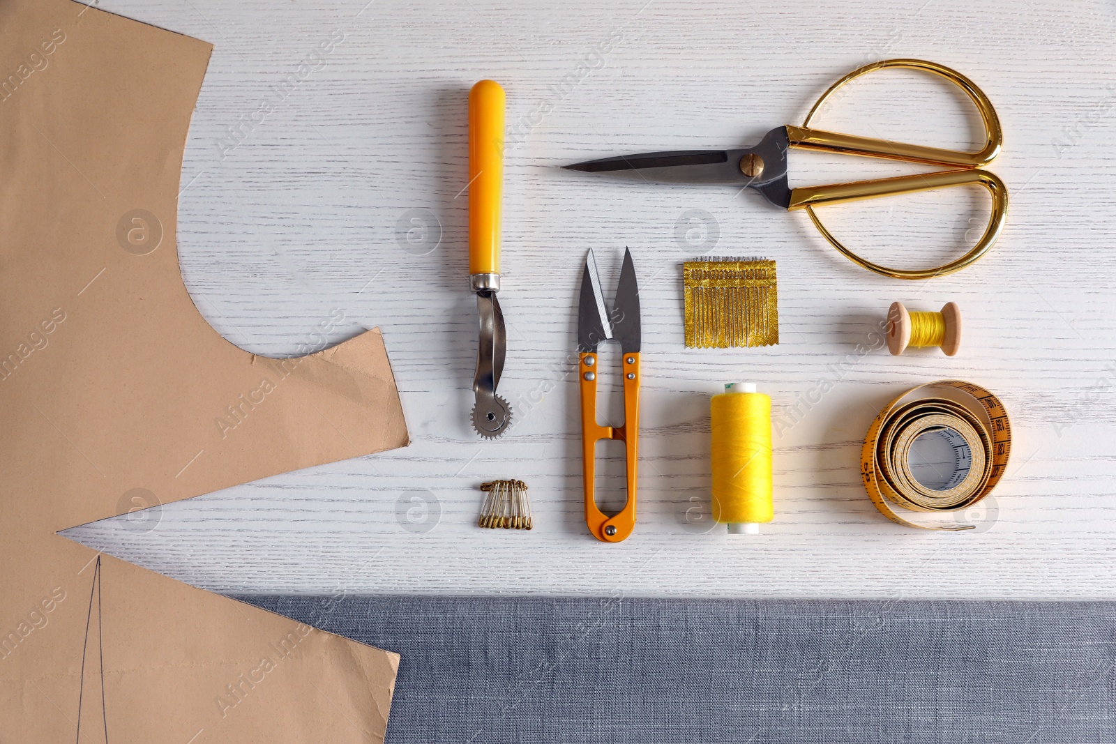 Photo of Set of sewing supplies and accessories with fabric on white wooden table, flat lay