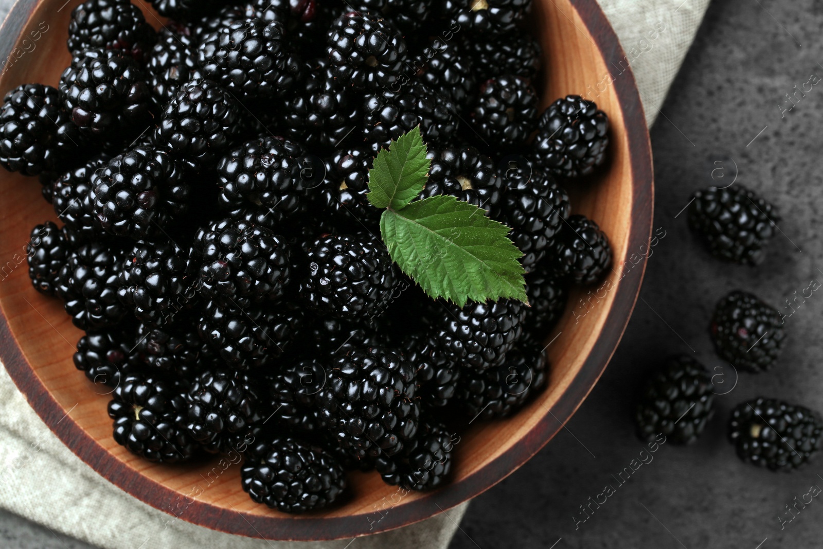 Photo of Bowl with fresh ripe blackberries on dark grey table, flat lay