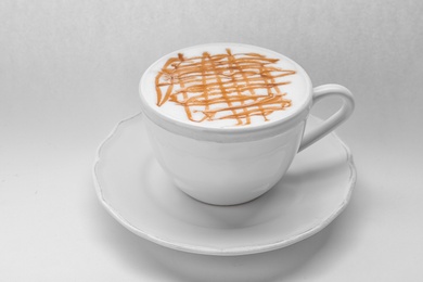 Cup of tasty caramel macchiato on white background