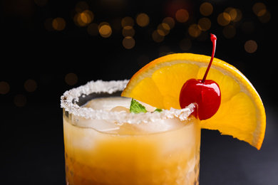 Fresh alcoholic Tequila Sunrise cocktail against blurred lights, closeup