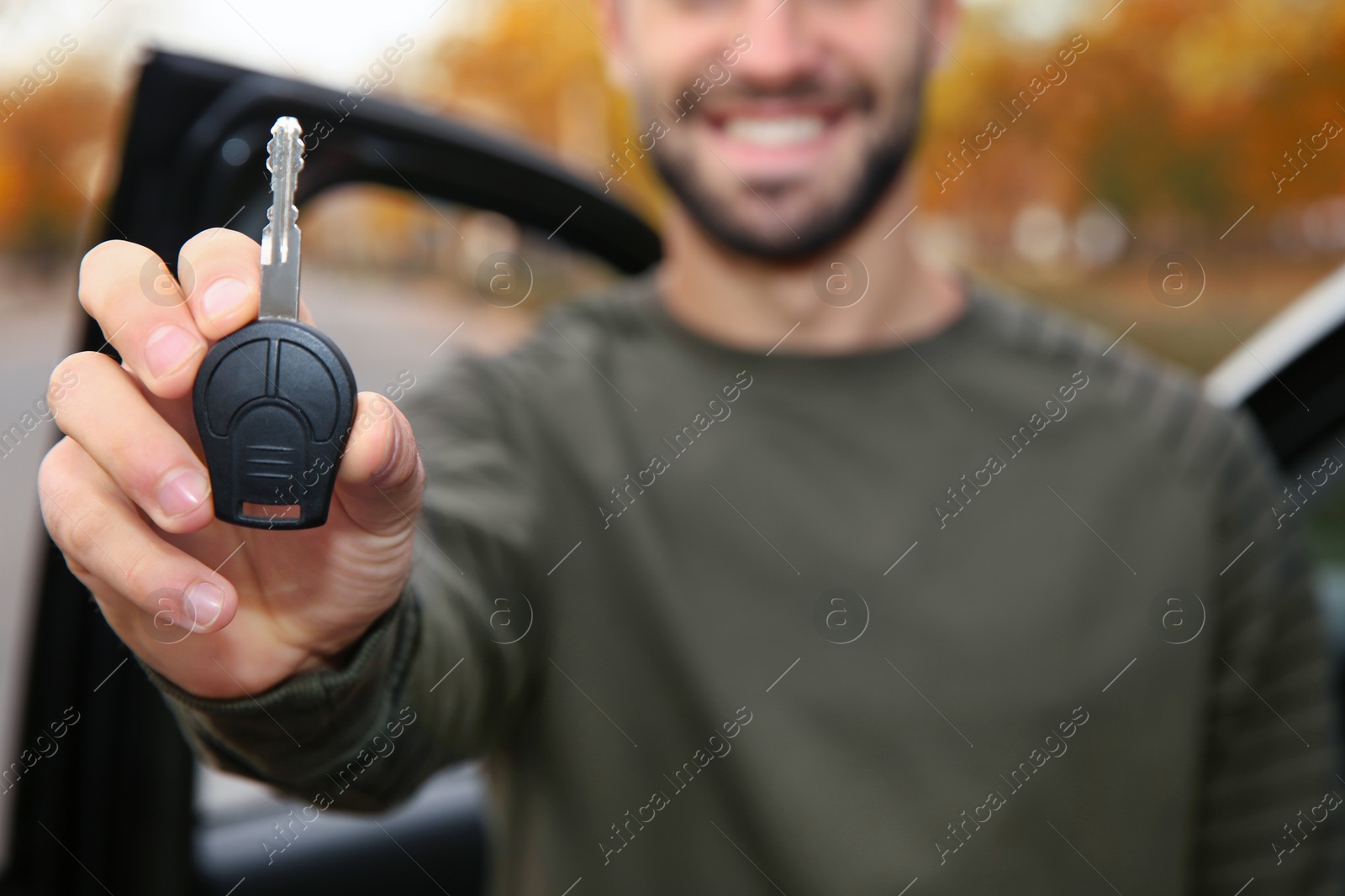 Photo of Young man holding car key near auto, closeup. Driving license test
