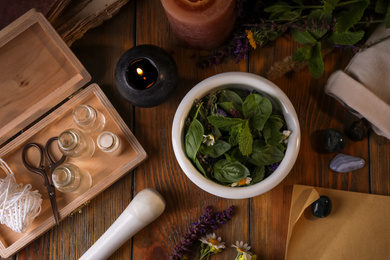 Photo of Flat lay composition with mortar, healing herbs and gemstones on wooden table