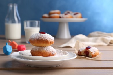 Photo of Hanukkah donuts with jelly and powdered sugar on wooden table, space for text