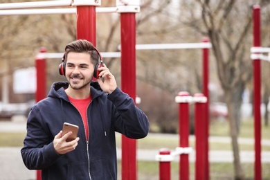 Photo of Young man with headphones listening to music on sports ground